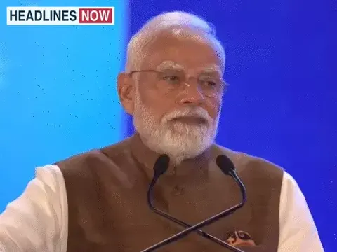 नीले बैकग्राउंड के सामने खड़े व्यक्ति माइक के पास भाषण देते हुए